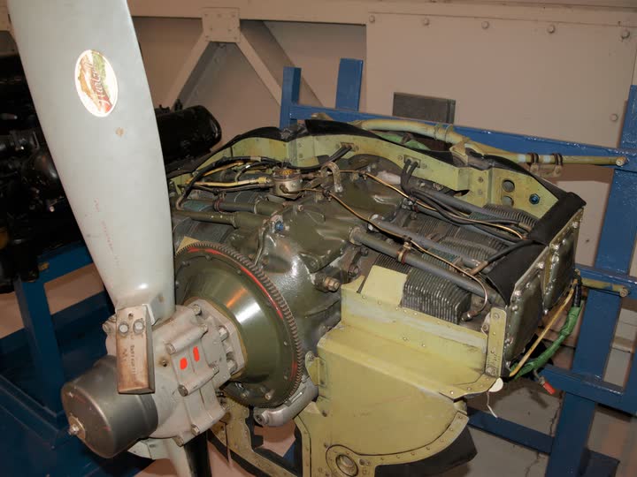 Vintage piston aircraft engine with its propeller attached, mounted on a display stand