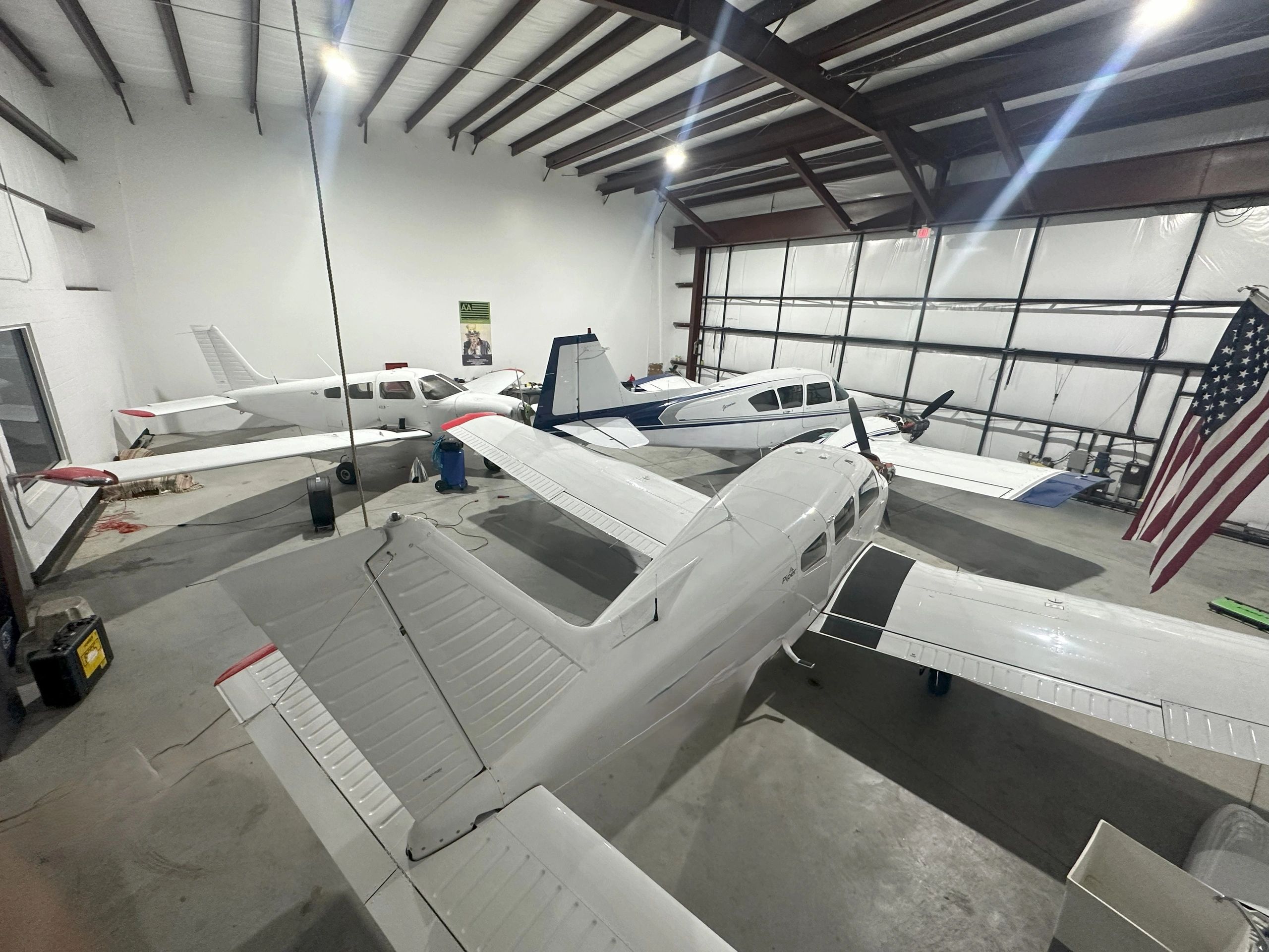 Alpha Company Aviation hangar interior with several aircraft and an American flag